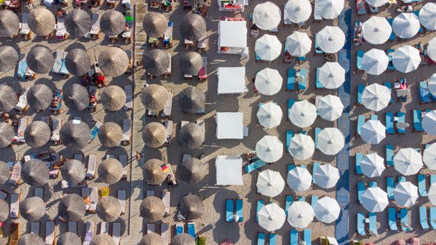 Aerial shot of beach umbrellas and sunbeds in Sarandë, Albania, during summer.