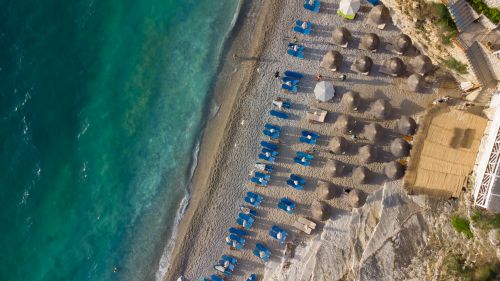Free Stunning aerial view of a tropical beach featuring rows of sunshades and loungers by turquoise waters. Stock Photo