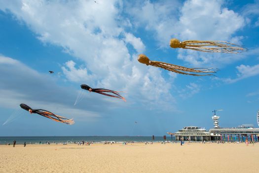 Colorful octopus-shaped kites soar in the sunny skies of Scheveningen beach, Den Haag.