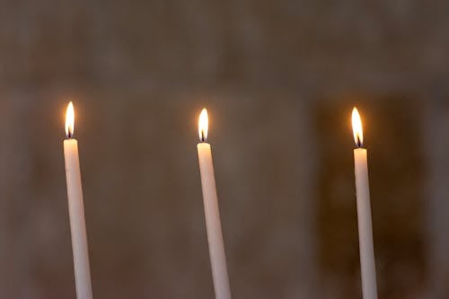 Three Burning Candles, against a Gray Background