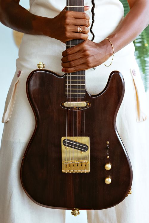 Free Close-up of woman elegantly holding a dark electric guitar, showcasing her hands and style. Stock Photo