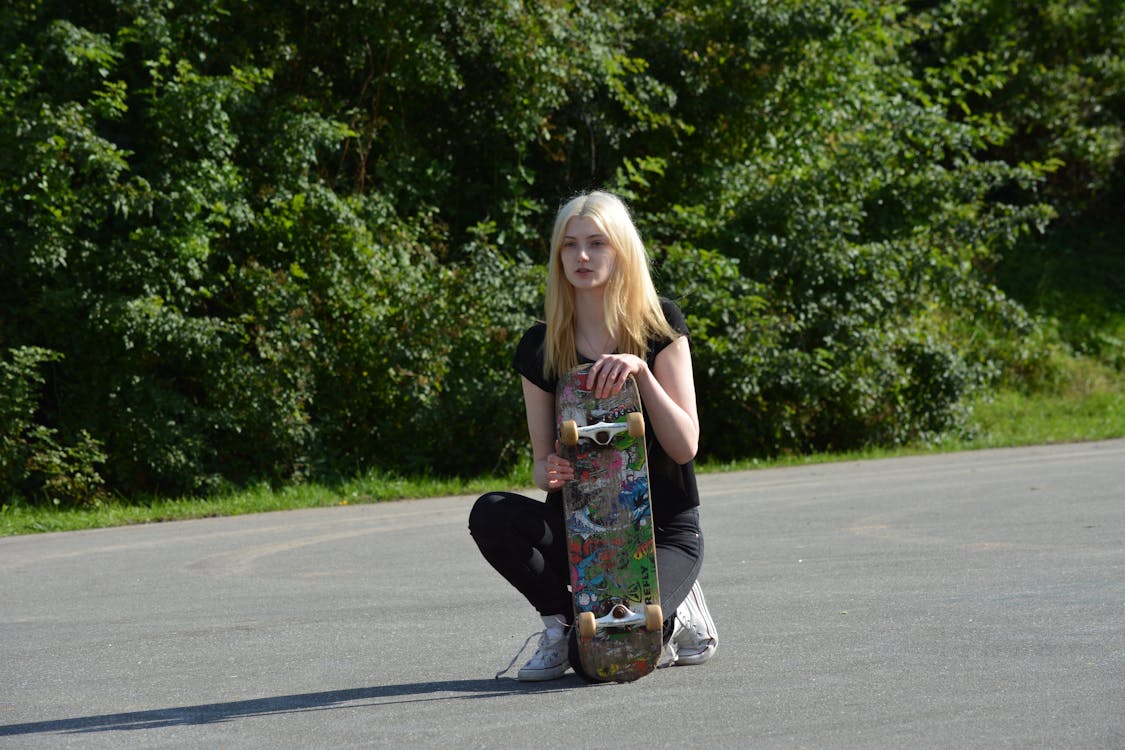 gratis Vrouw In Zwart Shirt En Broek Met Skateboard Overdag Stockfoto