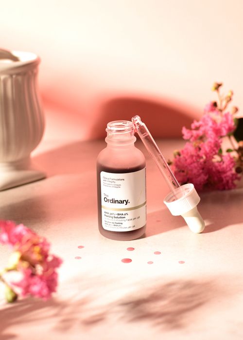 Free A skincare serum bottle with a pipette surrounded by pink flowers, ideal for health and beauty themes. Stock Photo