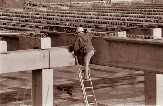 A construction worker climbs a ladder on an industrial site, captured in sepia tone for a vintage effect.