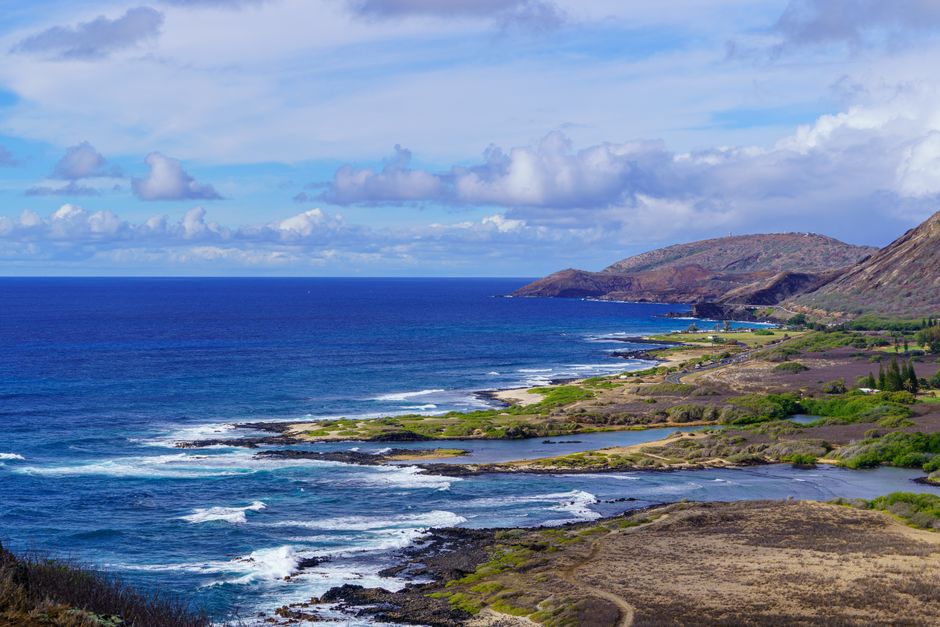 Stunning vista of Oahu's coastline with lush hills and blue ocean under a bright sky.