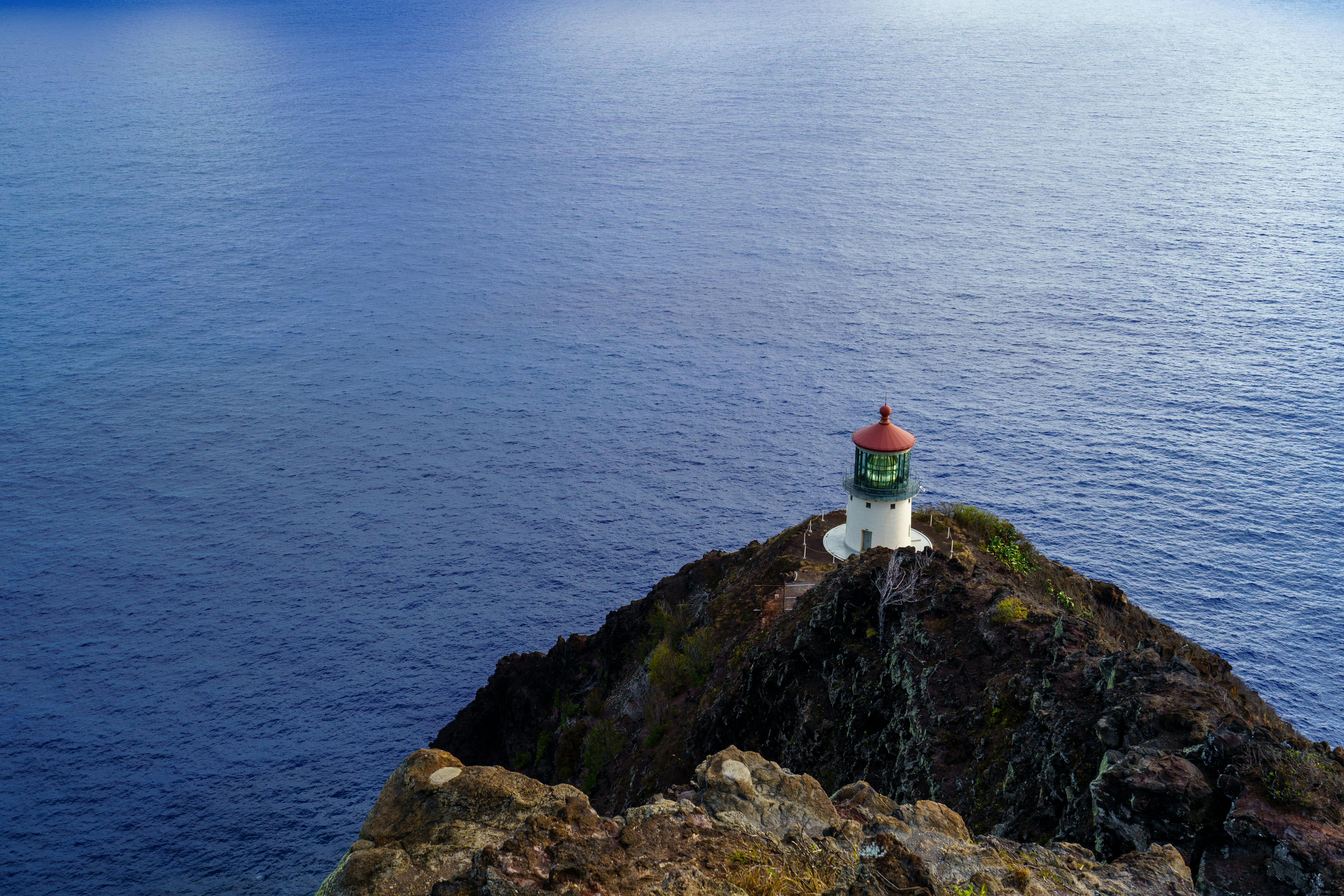 Makapuu Point Lighthouse with its red roof on the cliff below the Oahu lookout trail