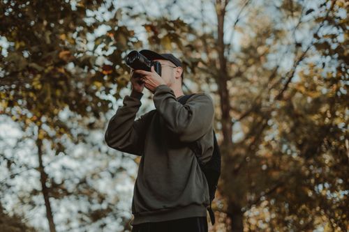 Free Man capturing moments in a serene autumn forest. Stock Photo