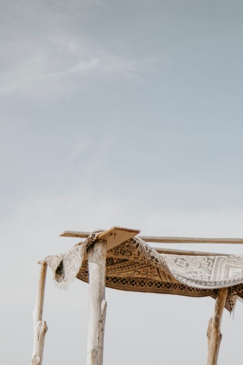 Free A rustic wooden canopy covered with a traditional carpet against a clear sky, evokes simplicity. Stock Photo