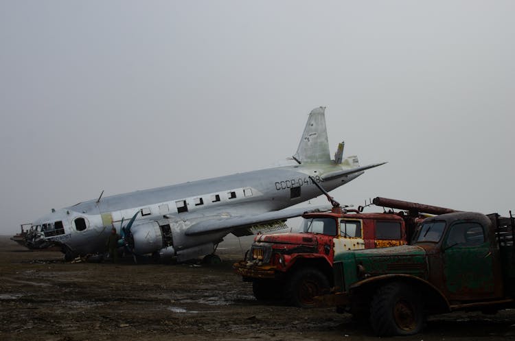 Airplane And Rusted Cars In Junkyard