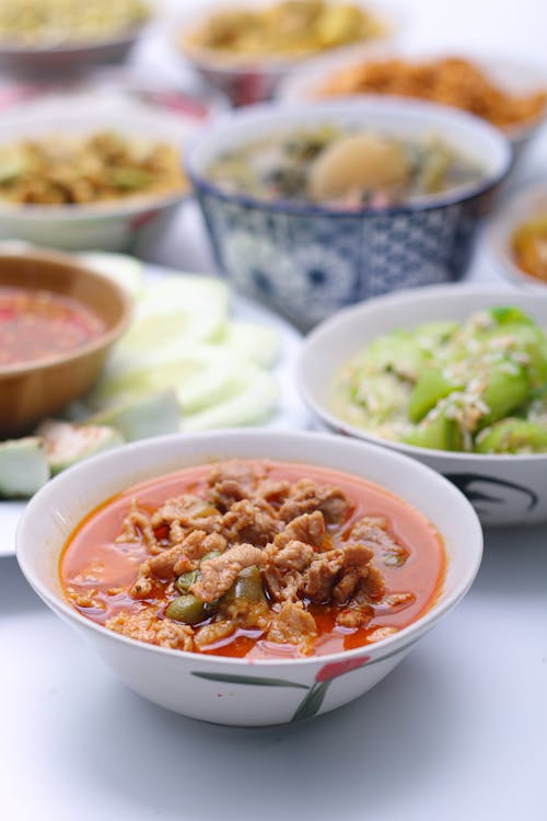 Panaeng Curry with Pork.Sliced M in red curry paste and coconut milk in a bowl on the set of group plates Thai food. Top view. Vertical view.