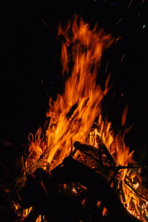 Free A large campfire blazing with intense flames against a dark night backdrop, emitting heat and light. Stock Photo