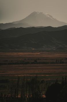 Serene landscape with mist-covered mountains and fields captured at dawn, a tranquil scene.
