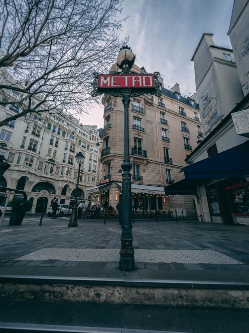 Free Classic Paris Metro sign in an elegant cityscape showcasing historic architecture. Stock Photo