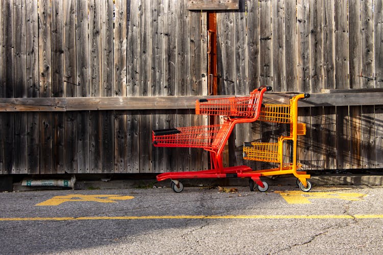 Two Red And Yellow Shopping Carts Beside Wall