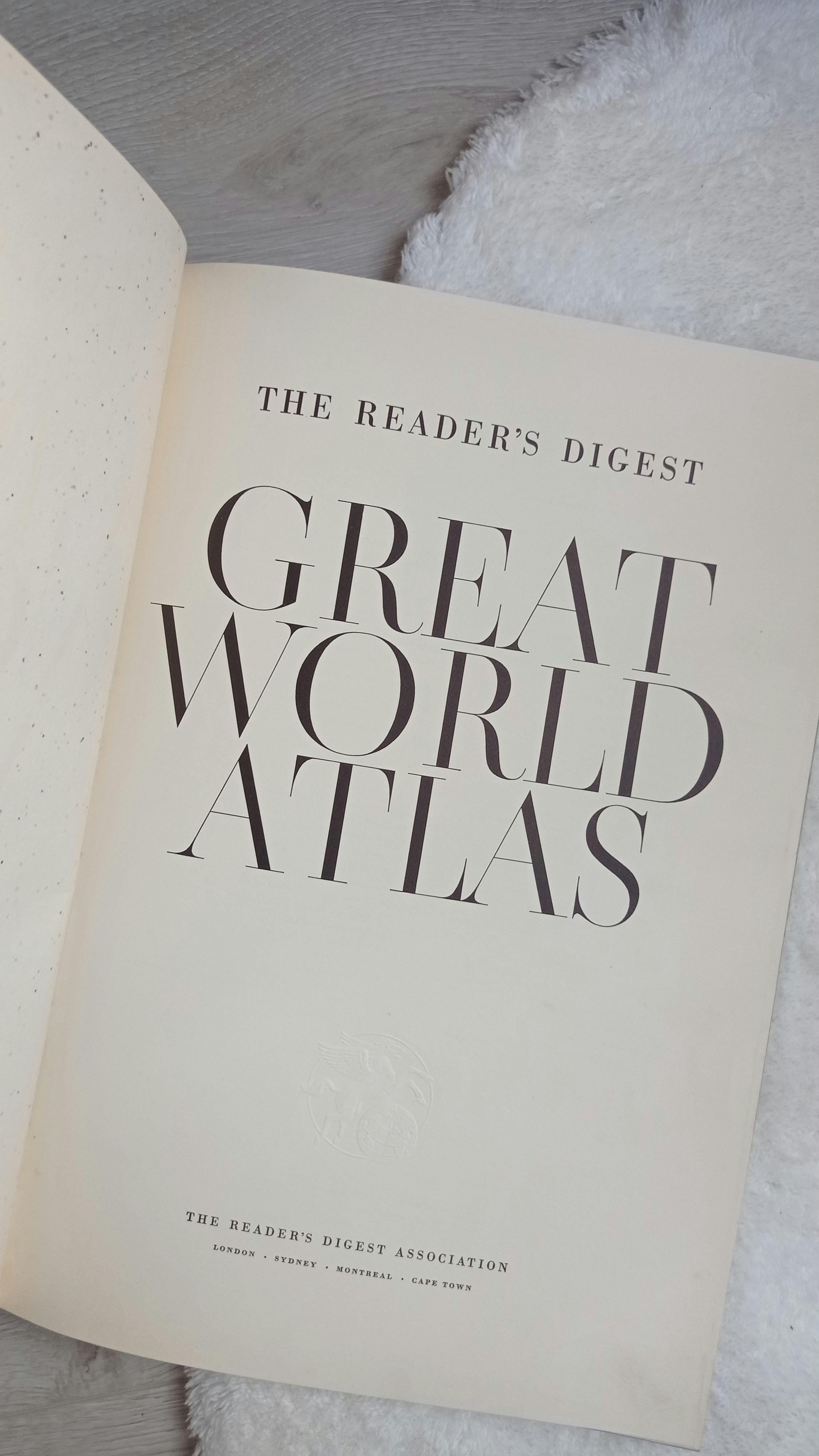 The Reader's Digest Great World Atlas first page open on a soft surface.
