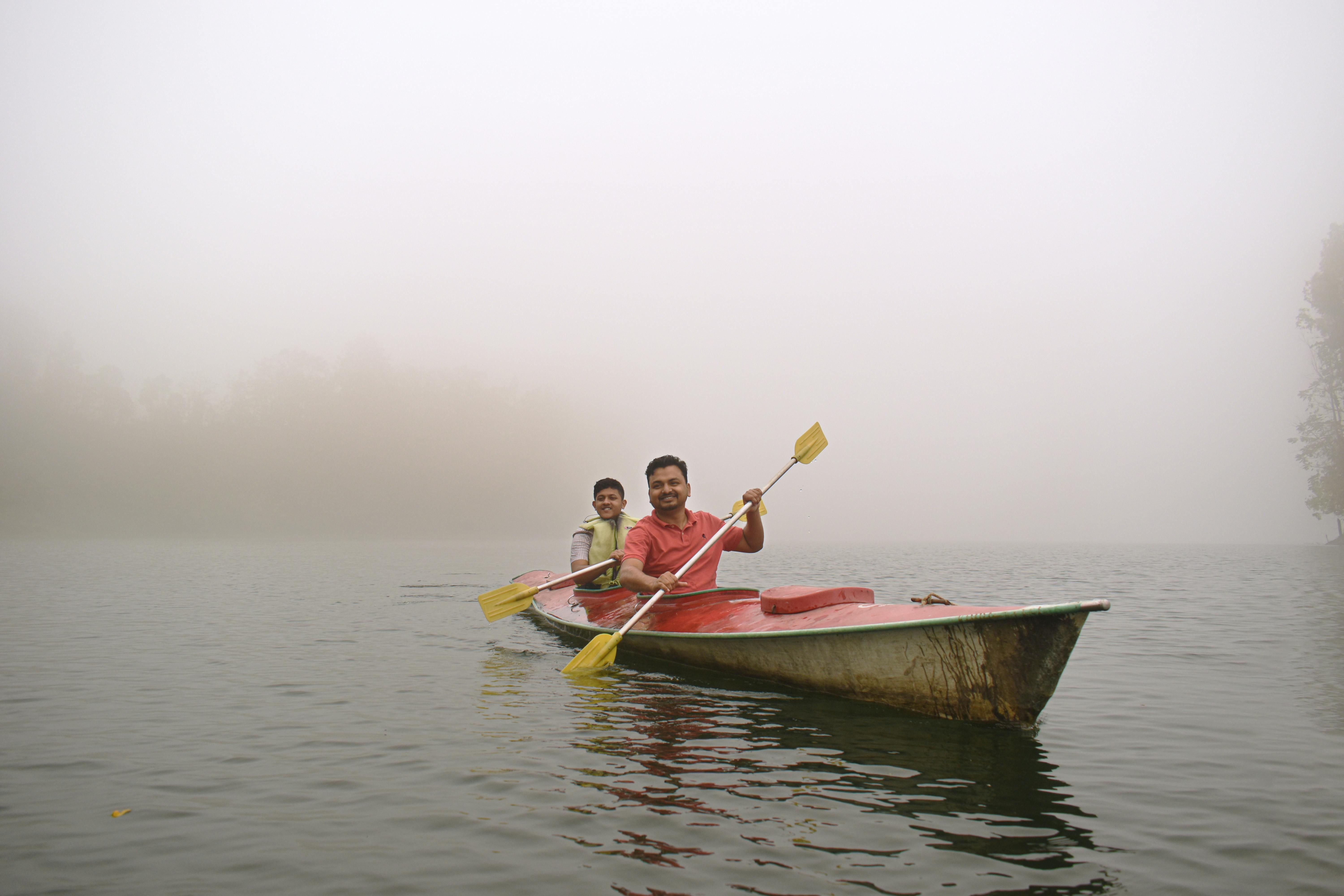 Two men enjoy kayaking on a foggy lake, adding a sense of adventure and tranquility to the scene.