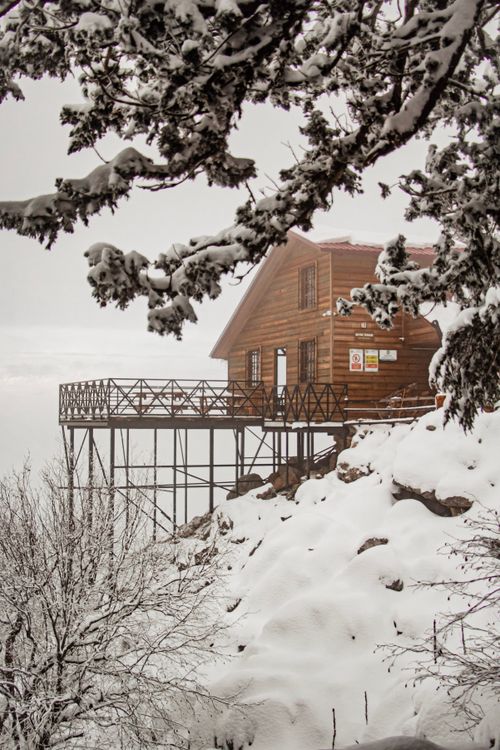 Free A picturesque wooden cabin covered in snow on a mountain slope in Aladağ, Türkiye. Stock Photo