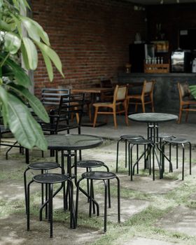 A charming outdoor bistro setting with empty tables and metal chairs surrounded by lush greenery. - Fotografer Sidoarjo