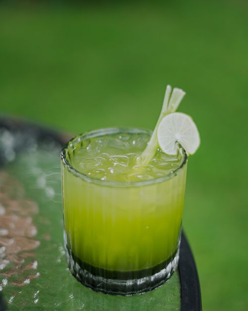 Free Close-up of a green drink with ice and lime on a glass table outdoors. Stock Photo