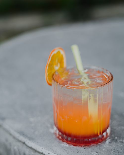 Free Bright citrus cocktail with an orange slice on a rustic surface, perfect for summer refreshment. Stock Photo