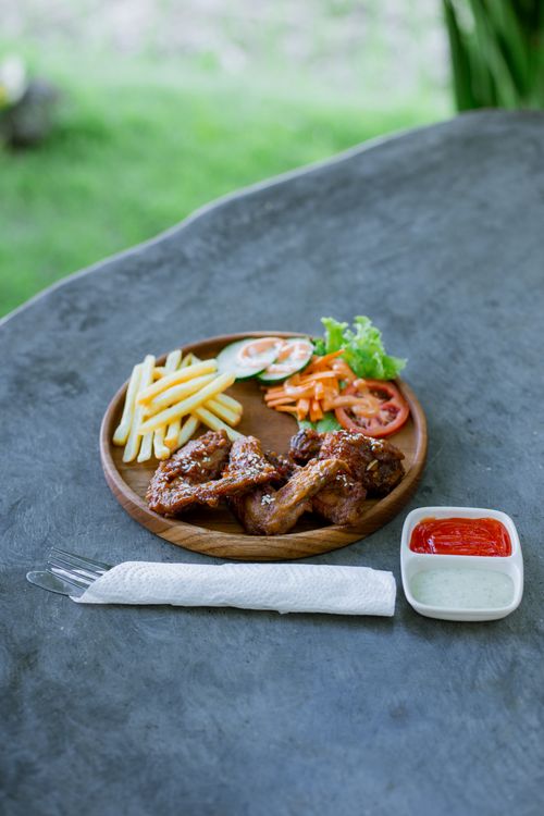 Free A savory grilled chicken meal served with fries, fresh salad, and sauces, captured outdoors. Stock Photo