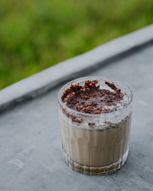 Free Glass of creamy coffee with chocolate topping on a concrete surface, outdoors. Stock Photo