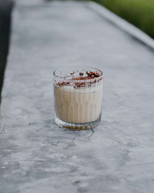 Free A creamy coffee drink topped with cocoa powder in a glass on a concrete surface. Stock Photo
