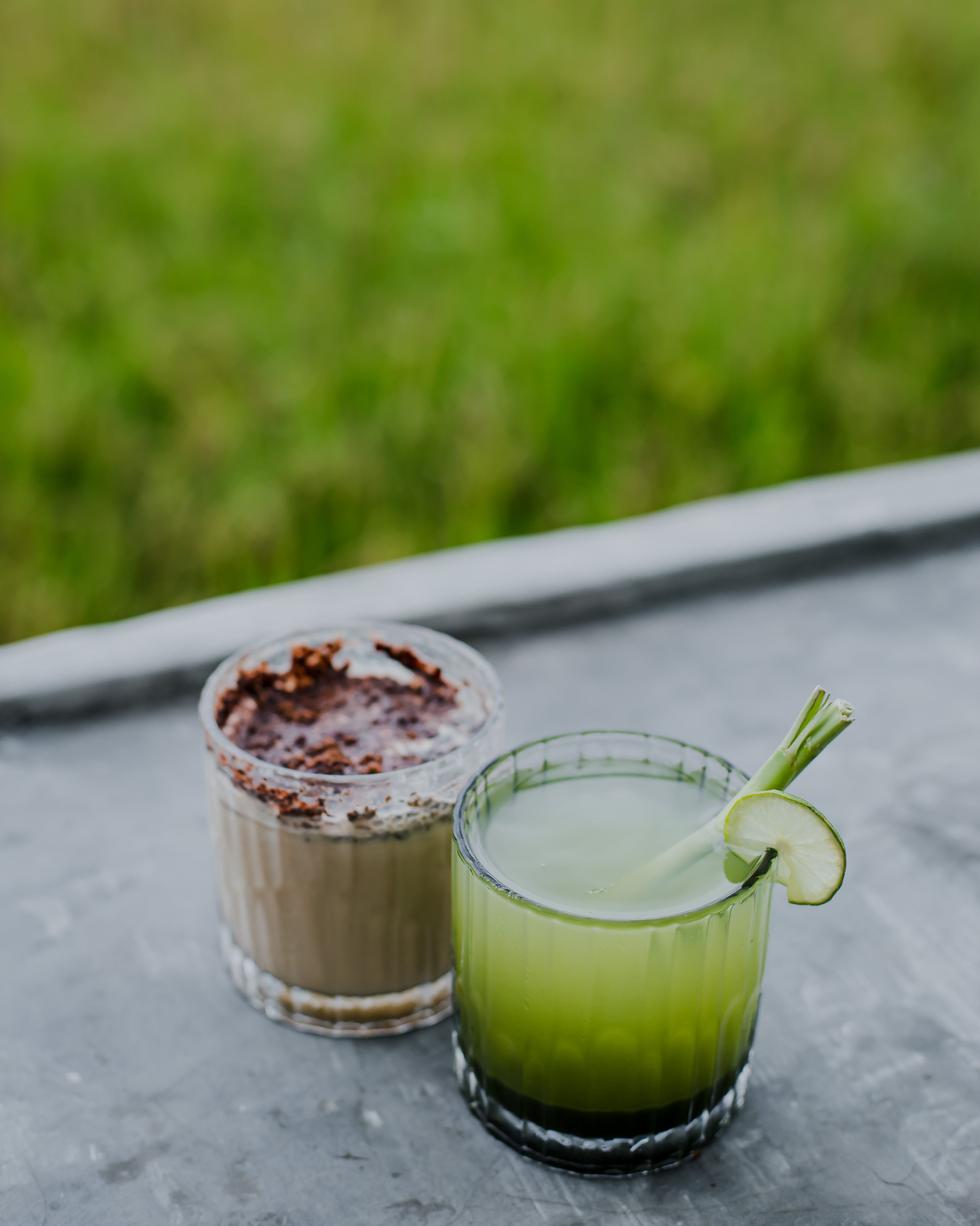 Cold-pressed green juices, wheatgrass shots and herbal teas arranged on a tray at a Bali detox retreat with rice terraces behind