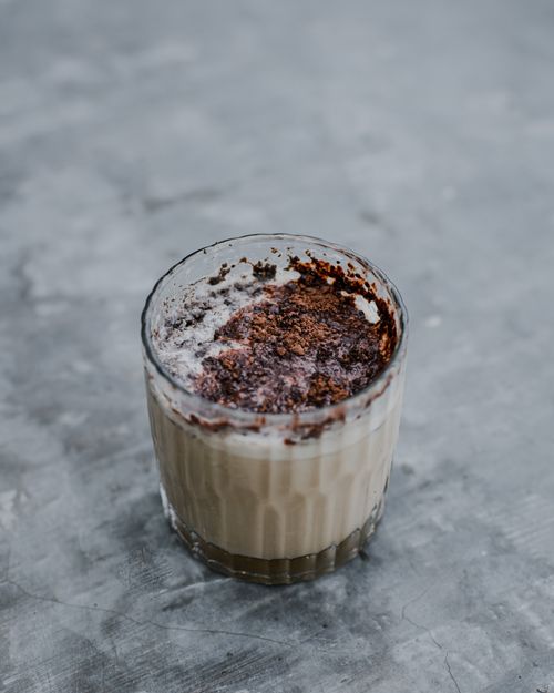 Free Glass of creamy coffee topped with rich chocolate powder on a gray surface. Stock Photo