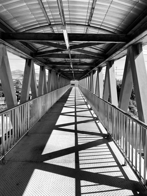 Free A striking black and white shot of a pedestrian footbridge with geometric shadows. Stock Photo