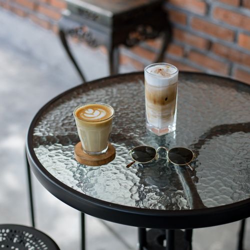 Free Two cups of coffee and sunglasses on a glass table in a cozy outdoor café setting. Stock Photo
