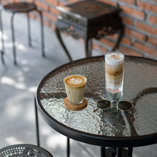 Free A chic cafe setup with lattes and sunglasses on a glass table, perfect for a relaxing brunch. Stock Photo