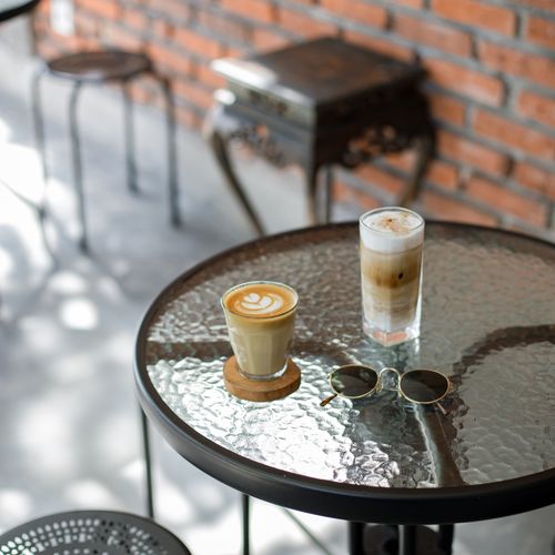 Free A glass table in a cafe with cappuccino, iced latte and sunglasses on a sunny day. Stock Photo