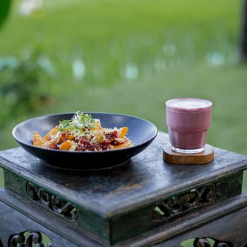 A delicious outdoor dining setup featuring nachos and a vibrant pink smoothie on a rustic table.