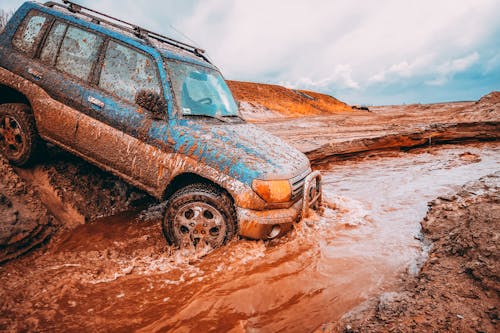 A Dirty Car Driving in Mud and Water 