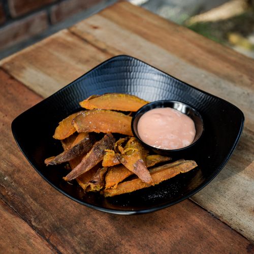 Free Crispy sweet potato fries served with creamy sauce on a rustic wooden table. Stock Photo