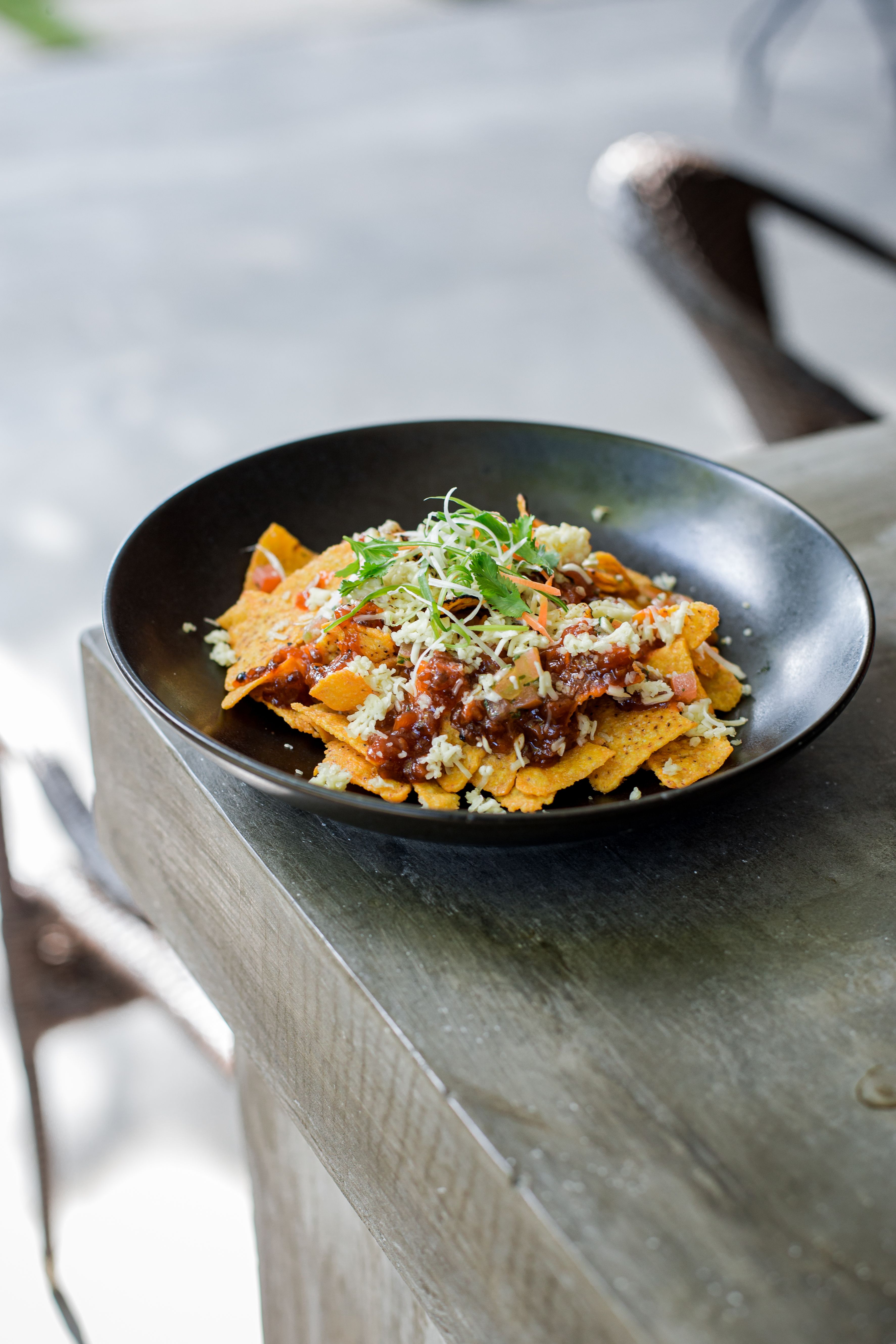 Tasty Mexican nachos topped with vegetables and cheese served on a rustic table.