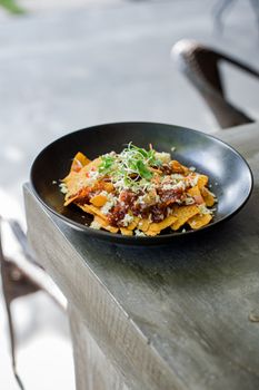 Tasty Mexican nachos topped with vegetables and cheese served on a rustic table.