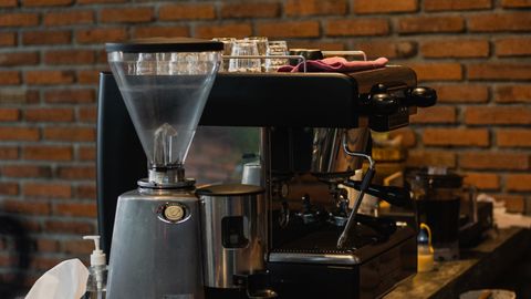 Inviting café interior with espresso machine and grinder on a wooden counter.
