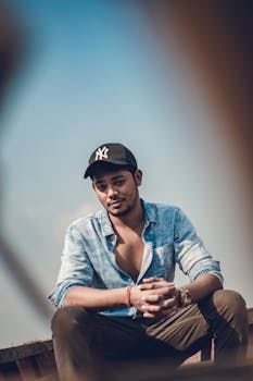 一名戴着帽子、穿着牛仔衬衫的男子随意地坐在户外