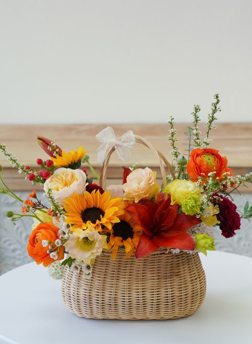 Free Elegant flower arrangement with sunflowers, roses, and seasonal blooms in a wicker basket. Stock Photo