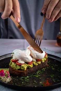 Close-up of avocado toast with poached eggs and tomatoes. A gourmet culinary presentation.