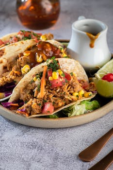 Close-up of freshly prepared tacos with vibrant toppings, served with sauce and lime.