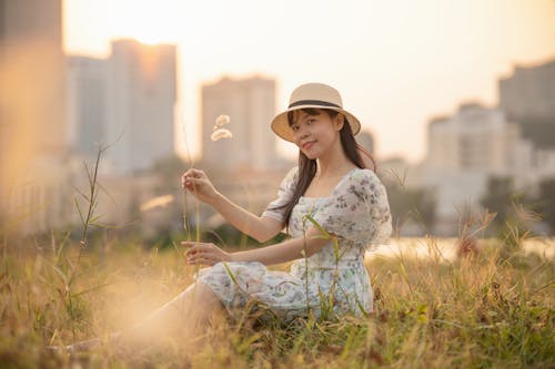 Woman Sitting in the Meadow and Holding a Grass 