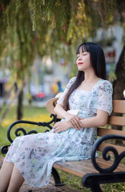 Woman Sitting on the Bench in a Park with her Eyes Closed 