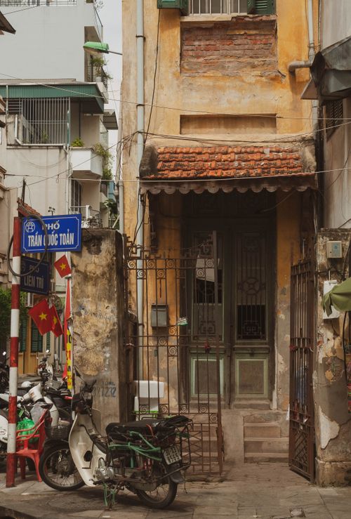 Free A narrow, weathered alleyway with rustic architecture and motorbikes in Hanoi, Vietnam. Stock Photo