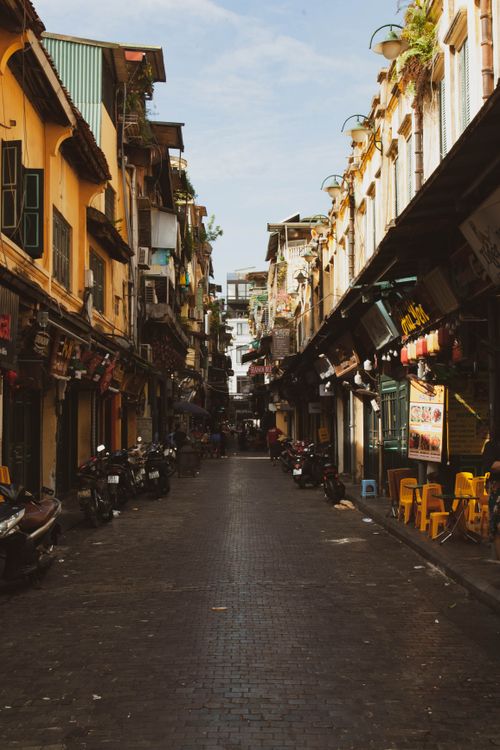 Free Charming narrow urban street in Vietnam featuring colorful buildings and motorbikes. Stock Photo
