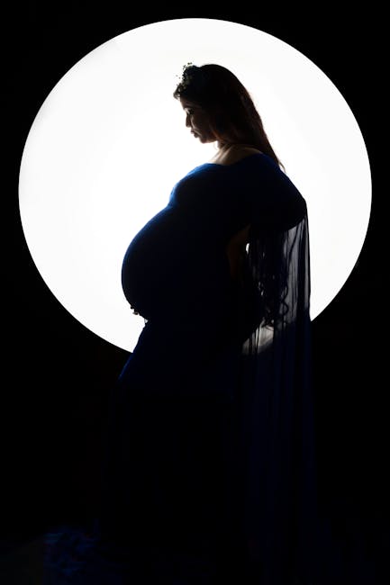 An artistic silhouette of a pregnant woman standing against a moonlit backdrop, creating a serene and ethereal scene.