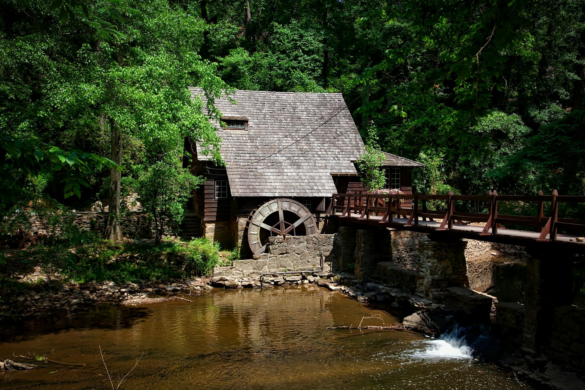 Beautiful historic mill house by a scenic creek with lush green foliage in summer.