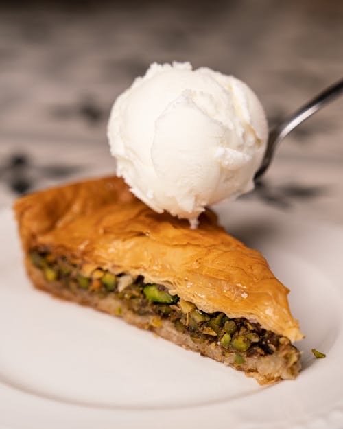 Close-up of a Slice of Cake with Pistachios and a Scoop of Ice Cream 